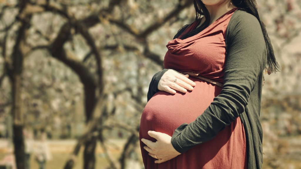 Image of pregnant woman cradling her abdomen.